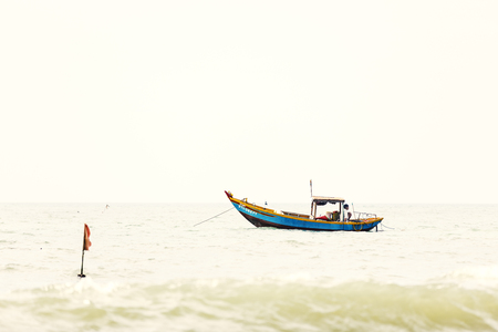 NAM TIEN, VIETNAM - FEBRUARY 21, 2018: Fisher with a wooden fishing boat on a sea in Nam Tien, Vietnamのeditorial素材