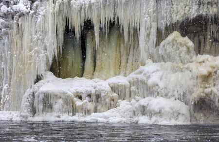 Snow and icicles on frozen waterfall in Estonia