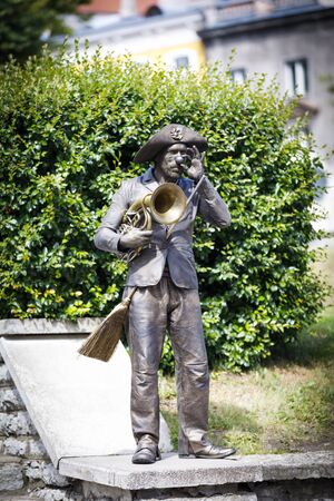 TALLINN, ESTONIA - JULY 05, 2019: Bronze colored living statue with a brush and music instrument stand on a wall in Tallinn, Estonia in July 2019のeditorial素材