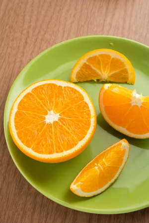 Half orange and slices of orange on green dish