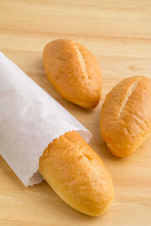 Bread in the paper bag on wooden tableの写真素材
