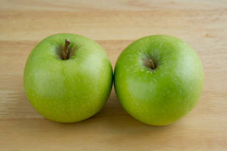 Two green apples on wooden tableの写真素材