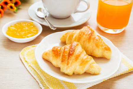 Croissants, coffee cup and juice on wooden tableの写真素材