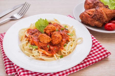 Spaghetti with meatballs in tomato sauce and deep fried chickenの写真素材