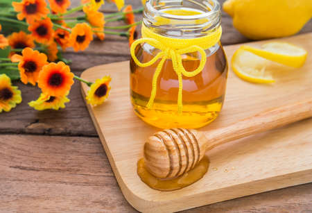 Honey dipper on wooden plate and jarの写真素材