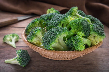Fresh broccoli in basket on wooden tableの写真素材