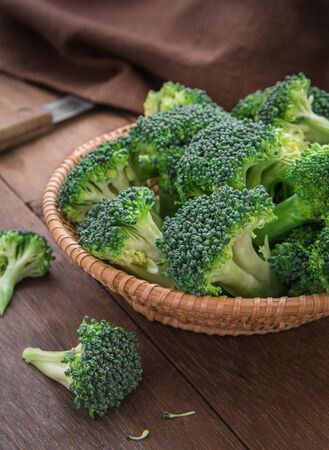 Fresh broccoli in basket on wooden tableの写真素材