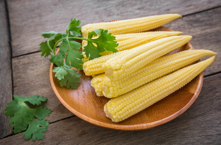 Fresh baby corn on wooden plateの写真素材