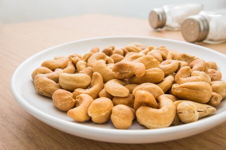 Cashew nuts on plate and salt shakerの写真素材