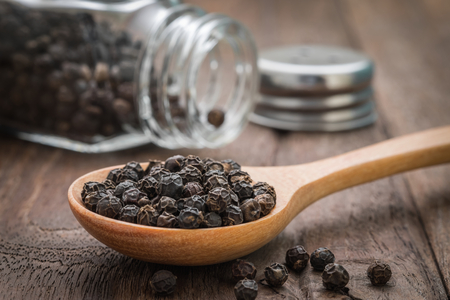 Black pepper on wooden spoonの写真素材