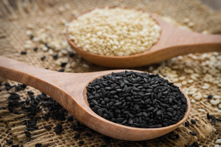 Black sesame and white sesame seed on wooden spoonの写真素材