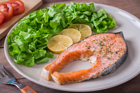 Grilled salmon steak covered with herb on plateの写真素材