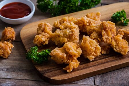 Crispy popcorn chicken on wooden board and dipping sauceの写真素材
