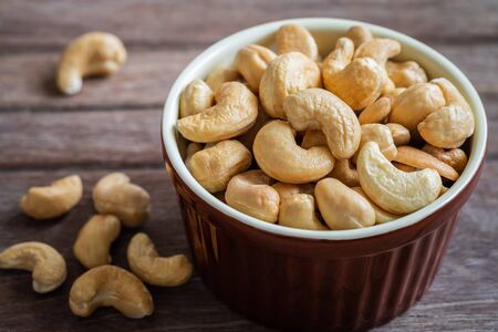 Cashew nut in brown bowl on wooden tableの写真素材
