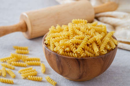 Raw fusilli pasta in wooden bowlの写真素材