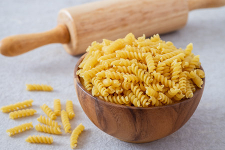 Raw fusilli pasta in wooden bowlの写真素材