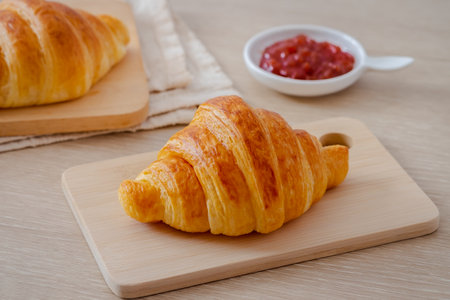 Fresh croissant on wooden board and jam on tableの写真素材
