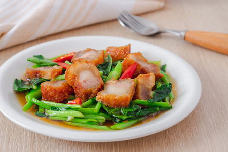 Stir fried kale with crispy pork in oyster sauce on white plateの写真素材
