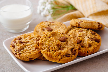 Chocolate chip cookies on white plate and glass of milkの写真素材