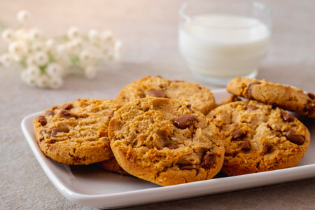 Chocolate chip cookies on white plate and glass of milkの写真素材