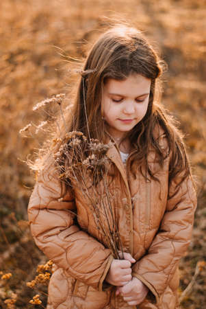 A girl with a smile. A dark-haired girl. The setting sun. evening light. dry grass. spring day.の写真素材