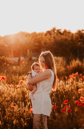 Mother and daughter in poppy field at sunset. Motherhood concept.の写真素材
