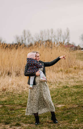 A young mother with a little daughter in her arms walks through the field.の写真素材