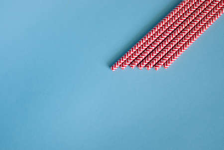 Red striped drinking straws on blue background, top view. Space for textの写真素材