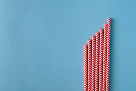 Red and white striped straws on blue background, top view. Space for textの写真素材