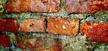 A wall of red bricks, rectangular, of varying sizes, large and small, glued together with gray...