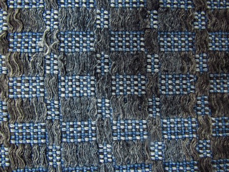 A handmade quilt, with white wool threads and various shades of blue, intertwined forming a tighter...