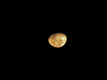 Looking at the dark sky, a crescent moon stands out in the immensity of the universe and it is possible, through the camera lens, to see the craters that exist on it.の写真素材