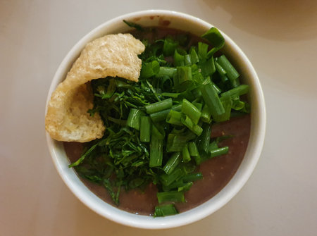 White bowl with bean broth, bacon and green onions, cabbage and cracklings, typical winter food,...