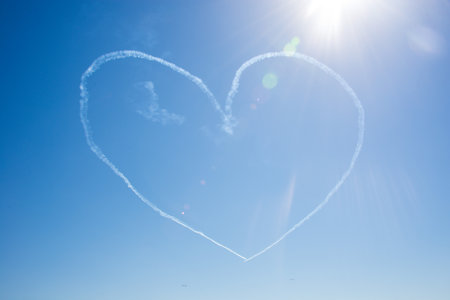 Heart shape made in the sky by a vintage aircraft, on a beautiful summer dayの写真素材