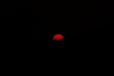 Red sun in the dark sky at night. Red sunset on a black background.の写真素材