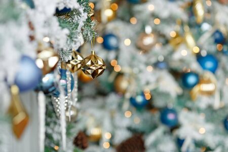 Branches of Christmas trees with gold and brown toys, balls, snow and garlands close-up on a blurred background bokeh, winter.の写真素材