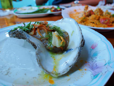 Eating raw oysters with lemon, garlic, herbs and chilli burn の写真素材