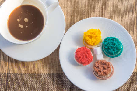 More colorful macarons and hot coffee in cup on fabric backgroundの写真素材