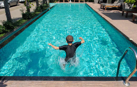 boy is jump5ing in the blue poolの写真素材