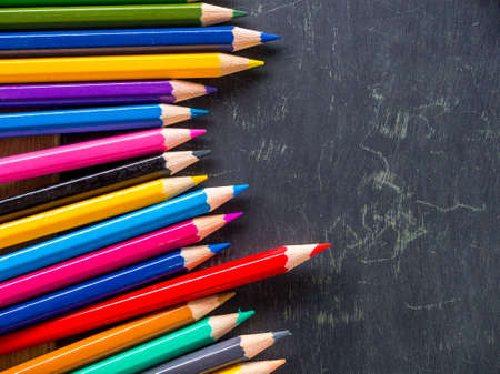 Row of colorful pencils on wooden background