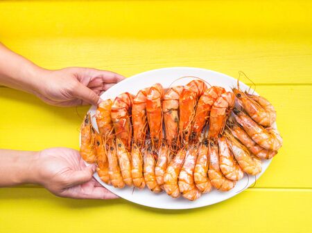 Handle on plate with fresh grilled shrimps on yellow wooden backgroundの写真素材