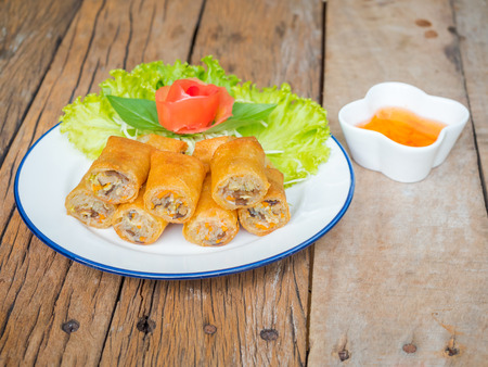 Fried spring rolls with vegetables and sweet sauce on wooden backgroundの写真素材
