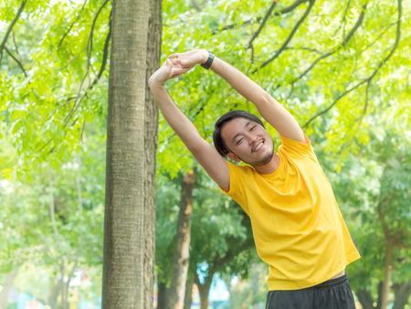 Young Asian man warm up his body before run in outdoor parkの写真素材