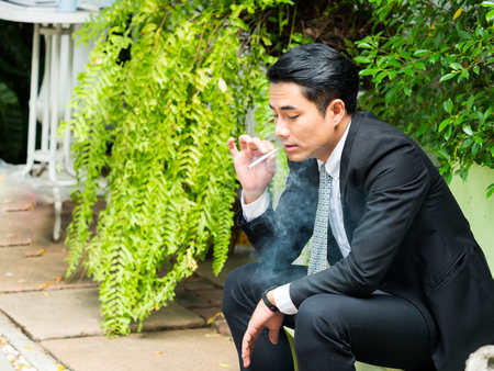 Young businessman smoking and thinking about business issuesの写真素材