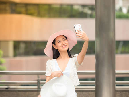 Tourist woman smiling and happy when she take a photo selfie by smartphoneの写真素材