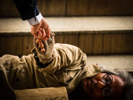 A businessman gives money to a homeless man sleeping on a ladder