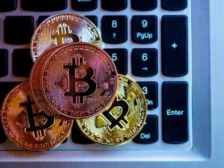 Bitcoins are copper, gold and silver, which are in the digital currency. On a keyboard backgroundの写真素材