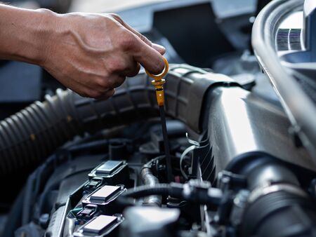 The mechanic's hand is measuring the engine oil level,  Which is according to the standard of engine maintenanceの写真素材