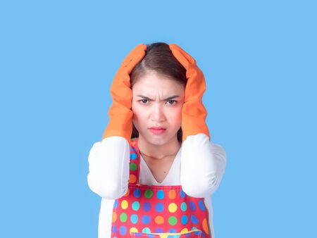 A beautiful Asian woman holds her hand in the head with stress and fatigue in cleaning the house, which is a job she doesn't likeの写真素材