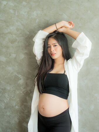 A beautiful pregnant woman stands in the room and poses as a model with a beautiful poseの写真素材